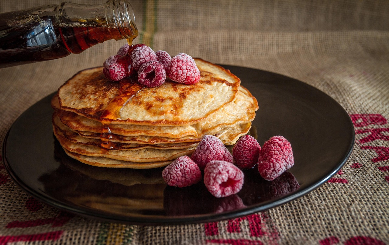 Pancake integrali morbidi serviti con frutta fresca e miele su un piatto bianco.