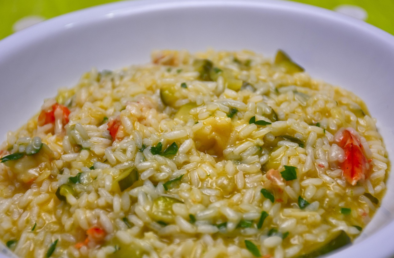 Risotto alla milanese cremoso con zafferano, impiattato elegantemente e decorato con una spolverata di parmigiano.