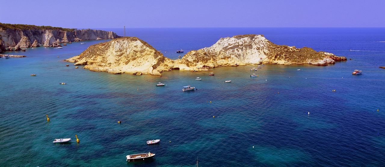 Vista panoramica di una caletta incontaminata a Ponza, accessibile solo via mare, con acque turchesi e scogliere.