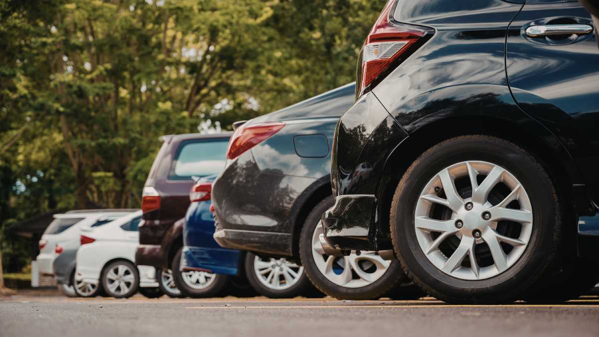 Meccanico controlla un'auto durante la revisione con documenti e attrezzi.